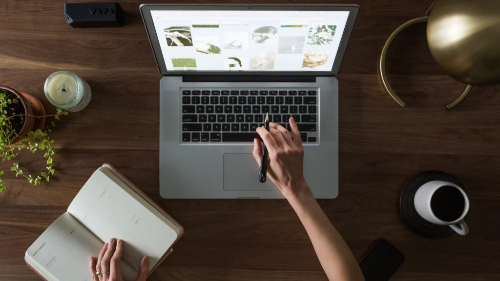 Vue de dessus d’un utilisateur prêt à réinitialiser un Mac avec un carnet de notes à la main