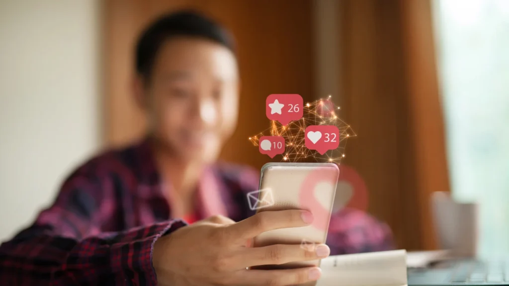 Jeune homme recevant des notifications sociales sur smartphone, montrant à quel GAFAM ces réseaux sociaux appartiennent-ils